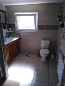 a bathroom with a toilet and a sink and a window at Chambre à la campagne in Hattenville