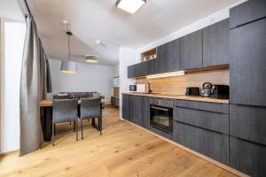 a kitchen with black cabinets and a table with chairs at Apartments Austria in Söll