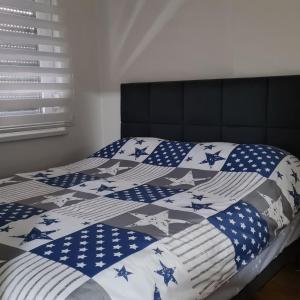 ein Bett mit einer blauen und weißen Decke mit Sternen in der Unterkunft Apartman 222 in Brčko