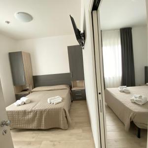 a hotel room with two beds and a mirror at Hotel Bed and Book in Rimini