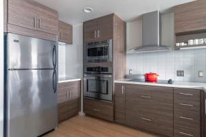 a kitchen with wooden cabinets and a stainless steel refrigerator at Lower Nob Hill 2BR w Roofdeck BBQ WD nr SFMH SFO-283 in San Francisco