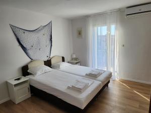 a bedroom with a large bed and a window at Apartmani Neva Supetar in Supetar