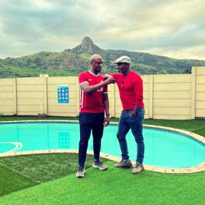 two men in red shirts standing next to a pool at Mantenga Hillview in Ezulwini