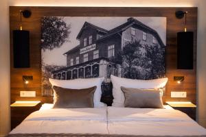 a bedroom with two beds and a painting of a house at Landhotel Am Rothenberg in Uslar