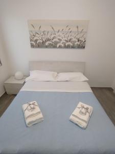 Una cama blanca con dos toallas encima. en RiDi Home Zona Ospedaliera, en Nápoles