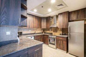 a kitchen with wooden cabinets and a stainless steel refrigerator at Goldcrest Views - 2BR Apartment - Allsopp&Allsopp in Dubai