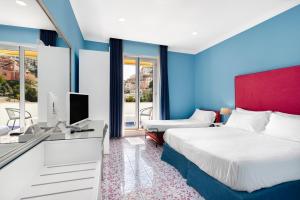 Schlafzimmer mit einem Bett und einem Schreibtisch mit einem TV in der Unterkunft Hotel Bougainville in Positano