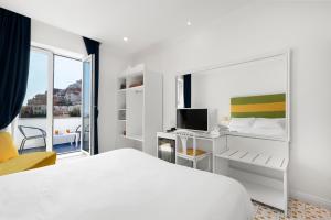 ポジターノにあるホテル ブーゲンヴィルのベッドとデスクが備わる白いホテルルームです。