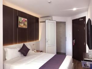 ein Schlafzimmer mit einem großen weißen Bett mit braunen Schränken in der Unterkunft Morris Hotel Nha Trang in Nha Trang