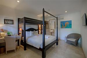 a bedroom with a canopy bed and a desk and a desk at OK Divers Resort & Spa in Padangbai