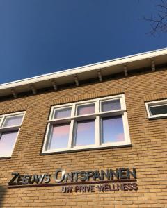 um edifício de tijolos com janelas e um sinal nele em Zeeuws Ontspannen Bed & Wellness em Middelburg