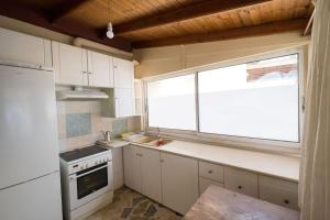 cocina con armarios blancos, fregadero y ventana en Σπίτι πάνω στο κύμα, en Katakolon