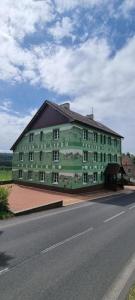 Pension Pod Lipou في Nová Ves v Horách: مبنى كبير أخضر على جانب الطريق
