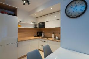 a kitchen with white cabinets and a clock on the wall at RentPlanet - Apartamenty Górna Resorts in Szklarska Poręba