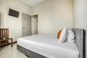 uma cama branca num quarto com televisão em KoolKost at Bypass Nusa Dua em Nusa Dua