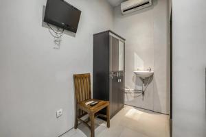 um quarto com uma televisão, uma cadeira e um lavatório em KoolKost at Bypass Nusa Dua em Nusa Dua