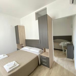 a small bedroom with two beds and a mirror at Hotel Bed and Book in Rimini
