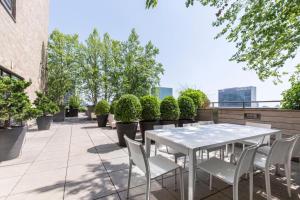 a white table and chairs on a balcony with plants at Murray Hill 1BR w Doorman Gym Pool Parking NYC-583 in New York