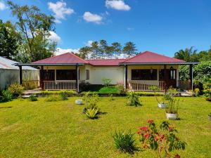 a house with a red roof and a yard at Ilasan cottage. in Tomohon