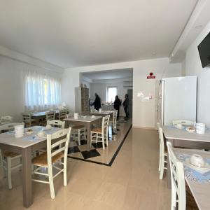 a dining room with white tables and chairs and people at Hotel Bed and Book in Rimini