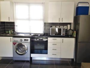 a kitchen with a washing machine and a microwave at The Rondebosch on Belmont in Cape Town