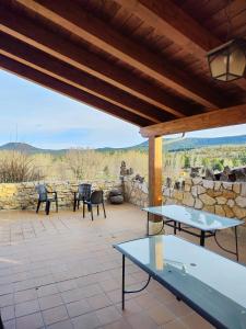 eine Terrasse mit Tischen und Stühlen und einer Steinmauer in der Unterkunft Casa el Escalerón in Uña