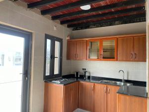 eine Küche mit Holzschränken und einem Fenster in der Unterkunft Rose Guesthouse in Al ‘Aqar