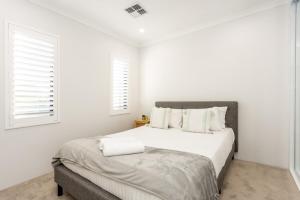 a white bedroom with a large bed and two windows at East Vic Park Glamour- EXECUTIVE ESCAPES in Perth