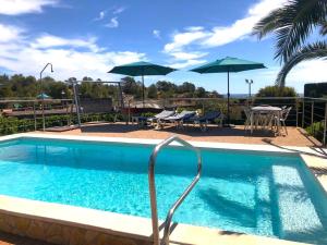 a swimming pool with umbrellas and a table and chairs at Villa Playa in L'Ametlla de Mar