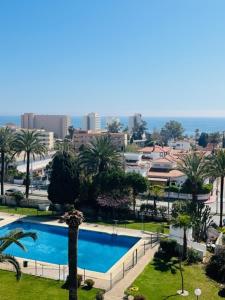 een groot zwembad met palmbomen in een stad bij Coqueto apartamento con vistas in Torremolinos