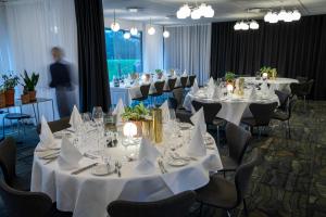 uma sala com mesas e cadeiras com toalhas de mesa brancas em Skanderborg Park em Skanderborg