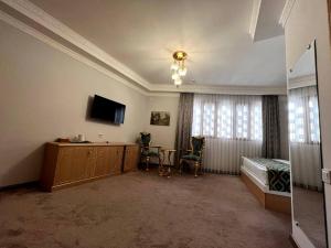 Schlafzimmer mit einem Bett, einem TV und einem Schreibtisch in der Unterkunft Hotel Shaherezade Garden in Buxoro