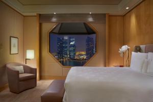 um quarto com uma grande cama branca e uma janela em The Ritz-Carlton, Millenia Singapore em Singapura