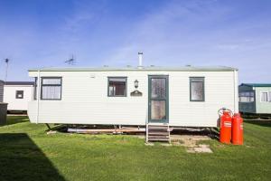 a white house sitting in a yard with two red fire hydrants at 6 Berth Caravan For Hire, Minutes From A Stunning Beach In Norfolk! Ref 21036f in Heacham