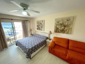a bedroom with a bed and a couch and a ceiling fan at Edificio Arco in Los Cristianos
