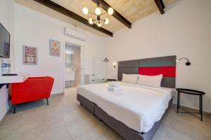 a bedroom with a large bed and a red chair at Casa Domenico 6 in Valletta