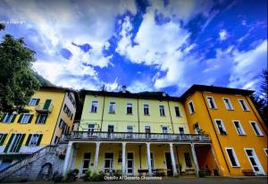 un gruppo di edifici gialli con un cielo nuvoloso sullo sfondo di Ostello Al Deserto a Chiavenna