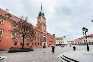 a large brick building with a clock tower on it at Dobra Old Town Apartment in Warsaw