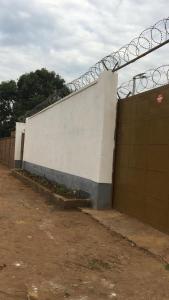 un bâtiment blanc avec un portail et une clôture dans l'établissement Chez Catherine et Gabriel, à Bangui