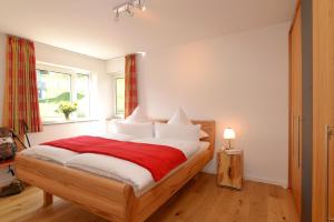 a bedroom with a bed with a red blanket and a window at 5 Sterne Ferienwohnung Bergahorn mit Sauna in Oberstaufen