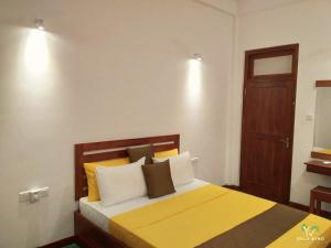 um quarto com uma cama com almofadas amarelas e brancas em Yala wind em Tissamaharama