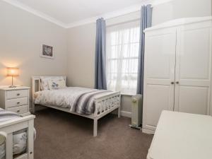 a white bedroom with a bed and a window at Sea Beach Cottage in Eastbourne