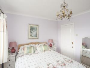 - une chambre blanche avec un lit et un lustre dans l'établissement Berllys, à Criccieth