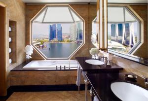 a bathroom with a tub and two sinks and a large window at The Ritz-Carlton, Millenia Singapore in Singapore