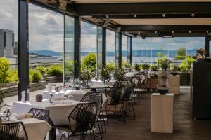 a row of tables and chairs in a room with windows at The Thief in Oslo