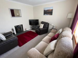 a living room with a couch and a tv at Self Catering house with lovely sea views, 44 Back in Vatsker