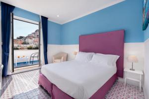 a bedroom with a large bed and a large window at Hotel Bougainville in Positano