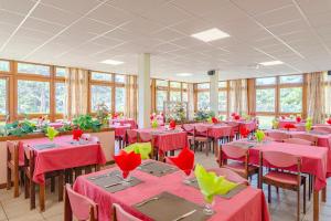 Hauteville-sur-MerにあるAzureva Hautevilleの赤いテーブルと椅子、窓のあるダイニングルーム