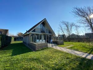una casa con puertas de cristal en un patio en Previnaireweg 20, en Callantsoog