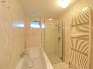 y baño con bañera, ducha y bañera. en Previnaireweg 20, en Callantsoog 13 fotos más